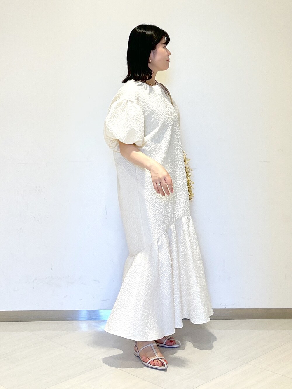 ホワイト系のワンピース、ホワイト系のサンダル、ベージュ系のトートバッグを着用したレディースの夏コーディネートの5枚目の写真