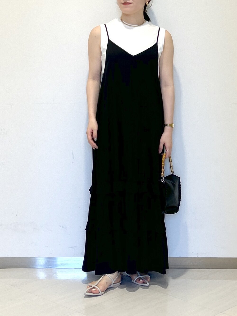 ブラック系のワンピース、ブラック系のショルダーバッグ、ホワイト系のサンダルを着用したレディースの夏コーディネートの2枚目の写真