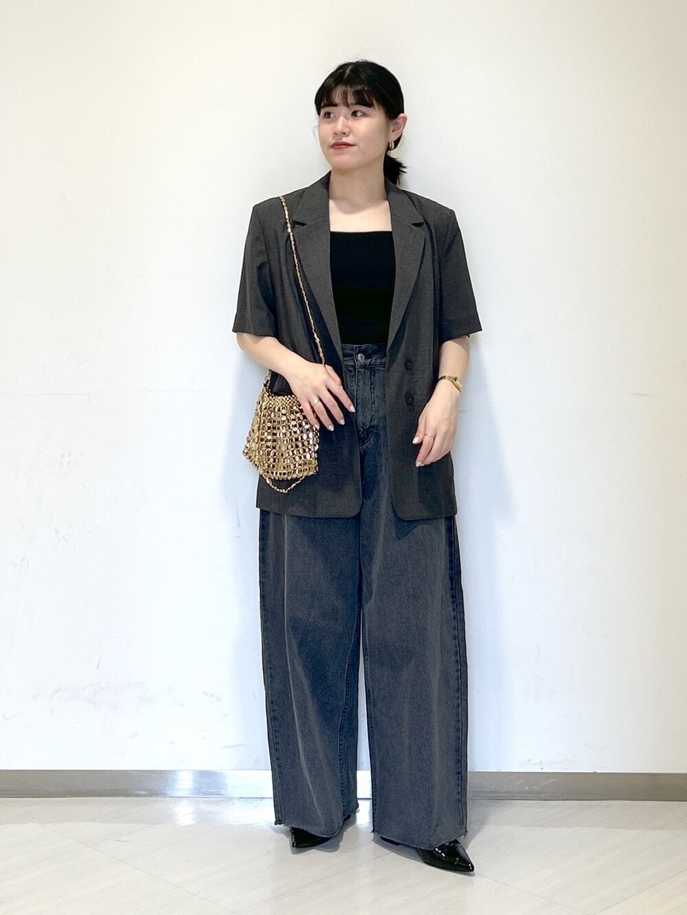 ゴールド系のショルダーバッグ、グレー系のテーラードジャケット、ブラック系のタンクトップを着用したレディースの夏コーディネートの6枚目の写真