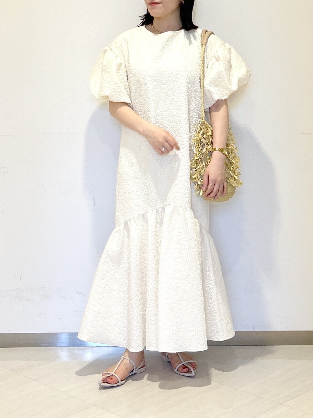 ホワイト系のワンピース、ホワイト系のサンダル、ベージュ系のトートバッグを着用したレディースの夏コーディネートの2枚目の写真