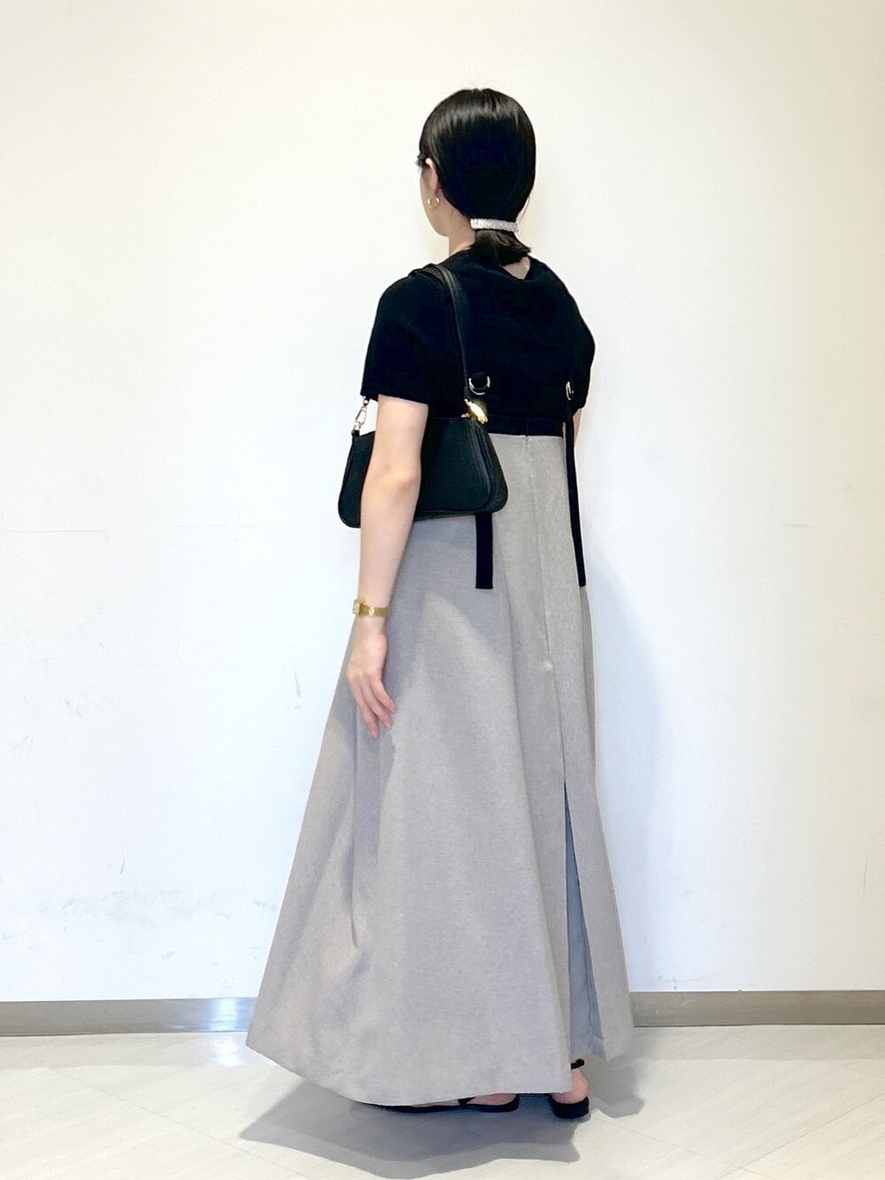 ブラック系のニット/セーター、ブラック系のショルダーバッグ、グレー系のジャンパースカートを着用したレディースの夏コーディネートの3枚目の写真