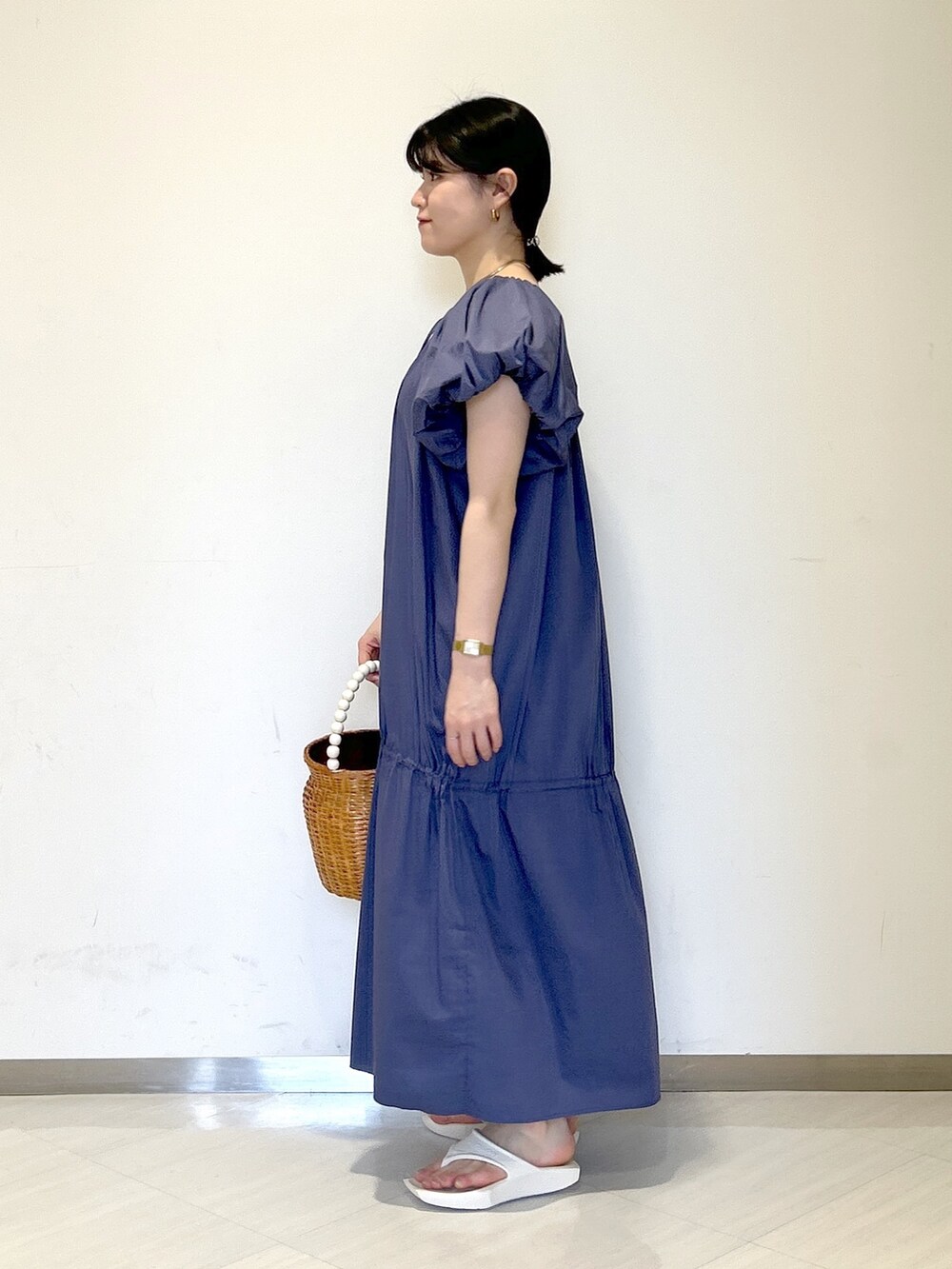 ブラウン系のかごバッグ、ホワイト系のサンダル、ブルー系のワンピースを着用したレディースの夏コーディネートの2枚目の写真