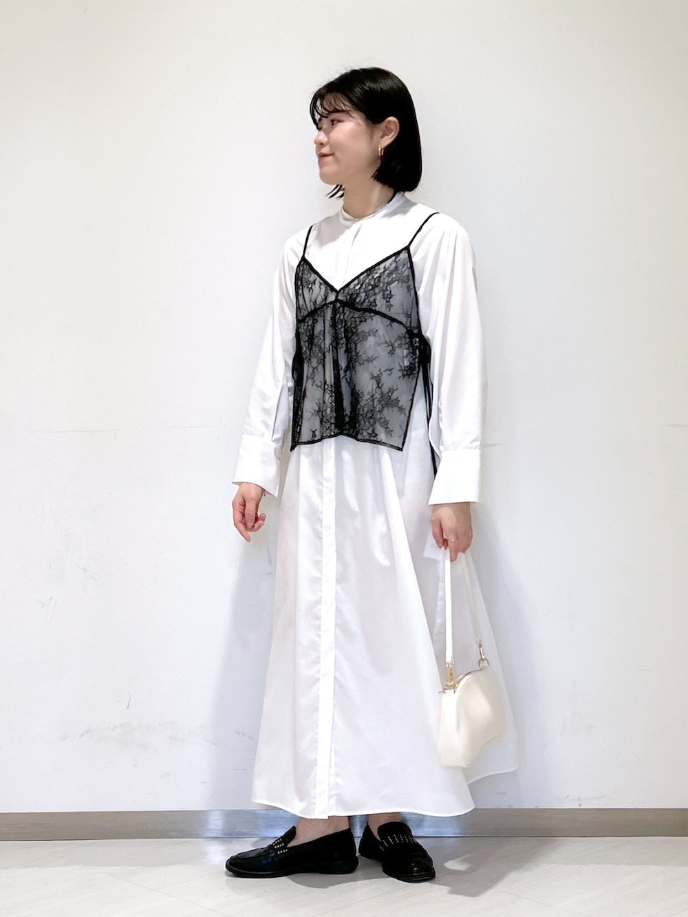 ホワイト系のシャツワンピース、ホワイト系のショルダーバッグ、ブラック系のローファーを着用したレディースの冬コーディネートの2枚目の写真