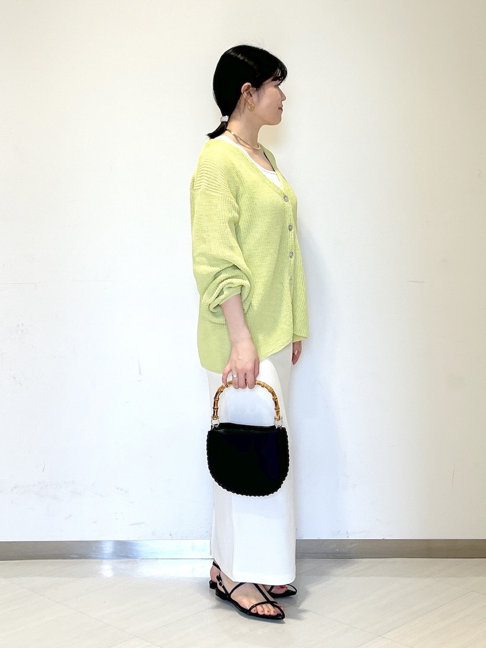 ホワイト系のタンクトップ、イエロー系のカーディガン/ボレロ、ホワイト系のスカートを着用したレディースの夏コーディネートの4枚目の写真