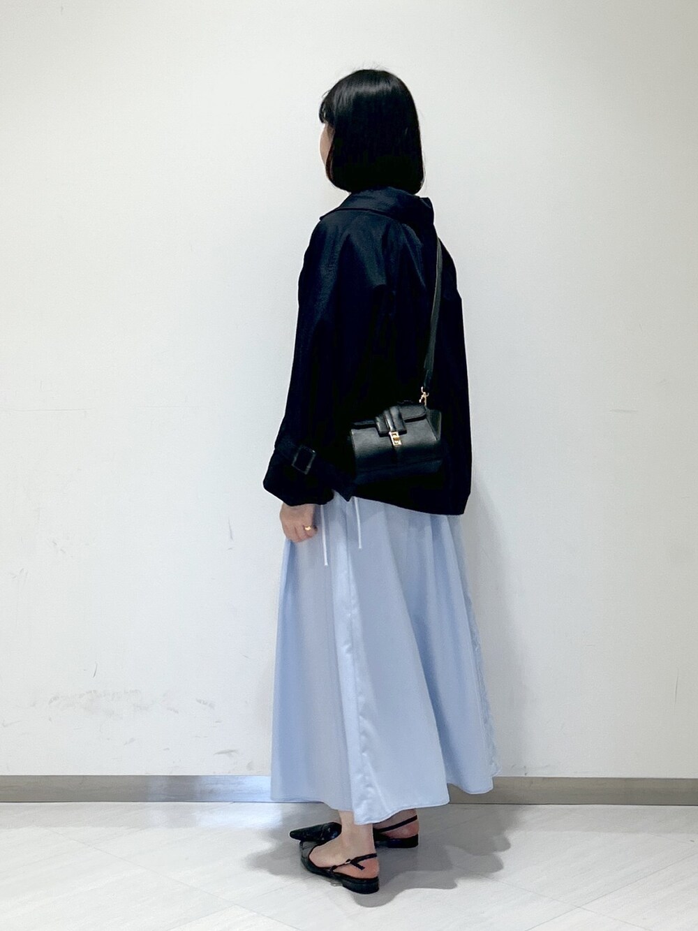 ブルー系のシャツワンピース、ブラック系のパンプス、ブラック系のショルダーバッグを着用したレディースの春コーディネートの2枚目の写真