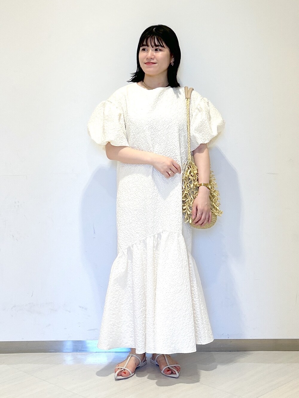 ホワイト系のワンピース、ホワイト系のサンダル、ベージュ系のトートバッグを着用したレディースの夏コーディネートの6枚目の写真