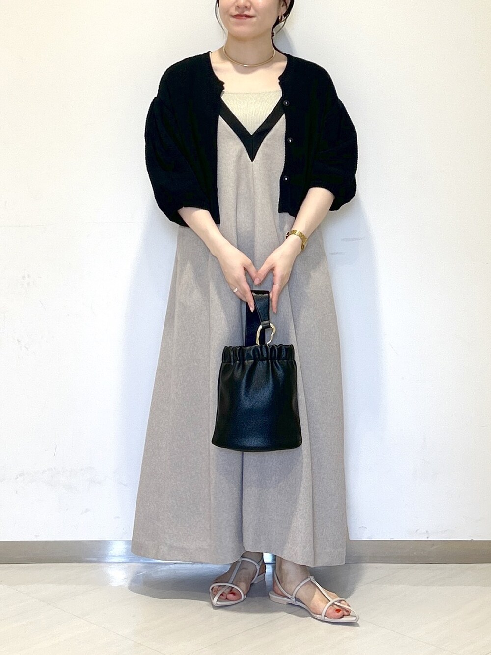 グレー系のジャンパースカート、ブラック系のカーディガン/ボレロ、ベージュ系のタンクトップを着用したレディースの夏コーディネートの2枚目の写真