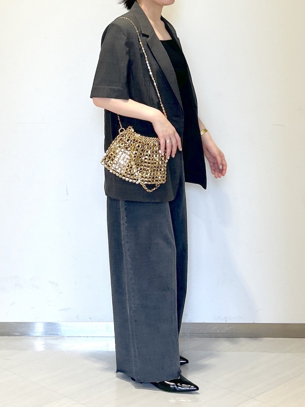 ゴールド系のショルダーバッグ、グレー系のテーラードジャケット、ブラック系のタンクトップを着用したレディースの夏コーディネートの5枚目の写真