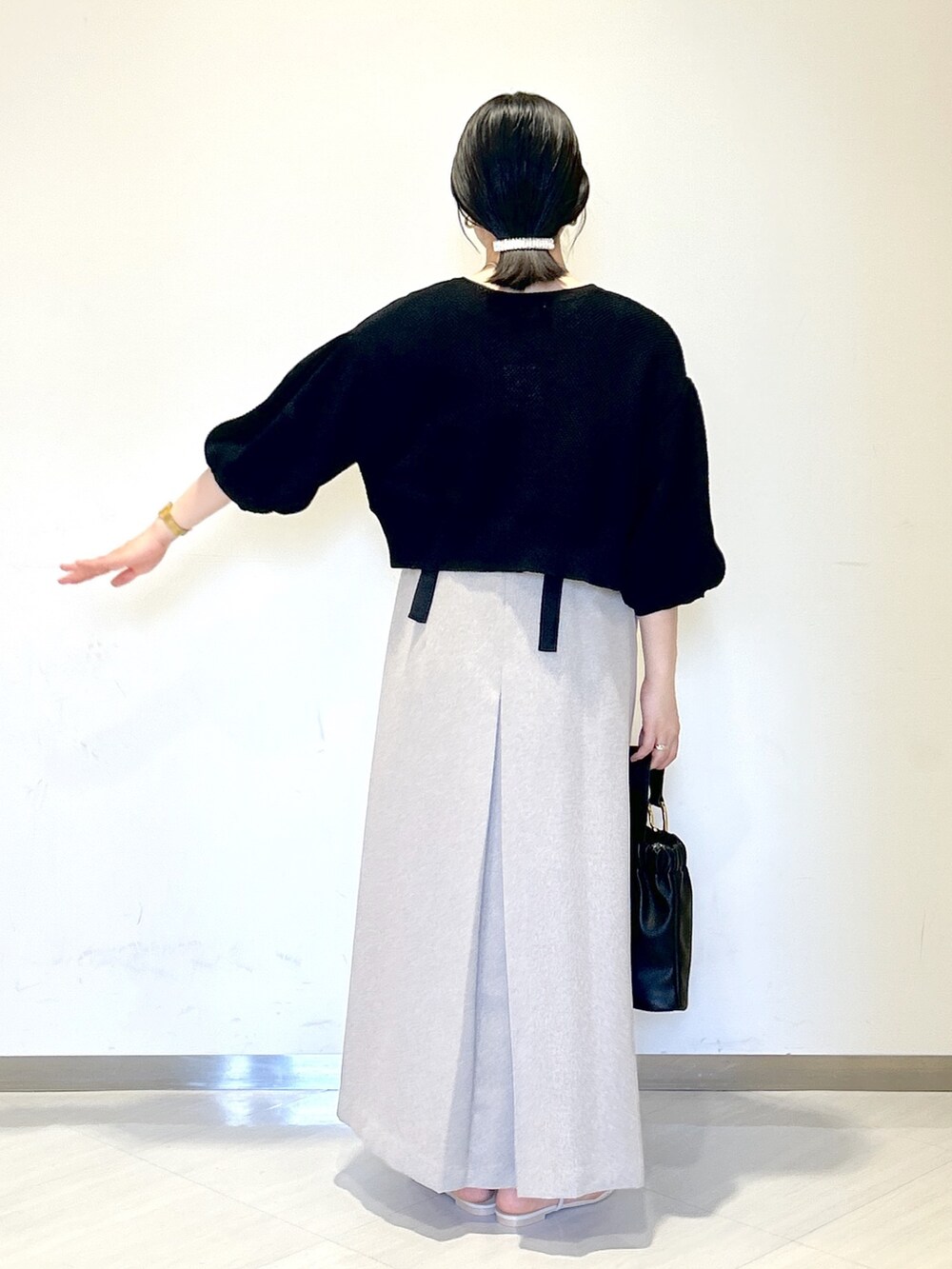 グレー系のジャンパースカート、ブラック系のカーディガン/ボレロ、ベージュ系のタンクトップを着用したレディースの夏コーディネートの4枚目の写真