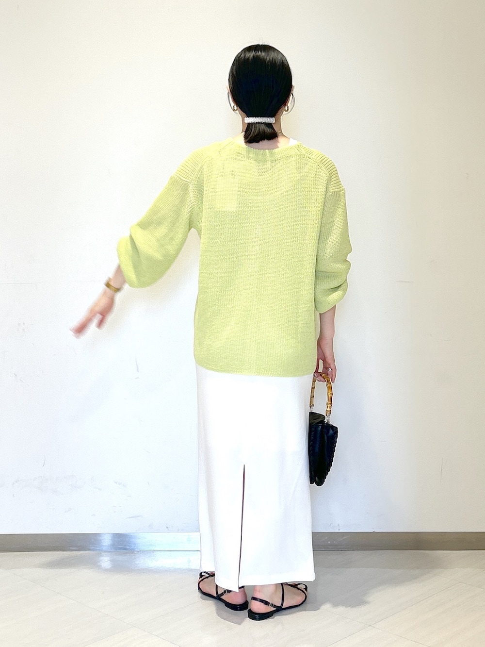 ホワイト系のタンクトップ、イエロー系のカーディガン/ボレロ、ホワイト系のスカートを着用したレディースの夏コーディネートの3枚目の写真