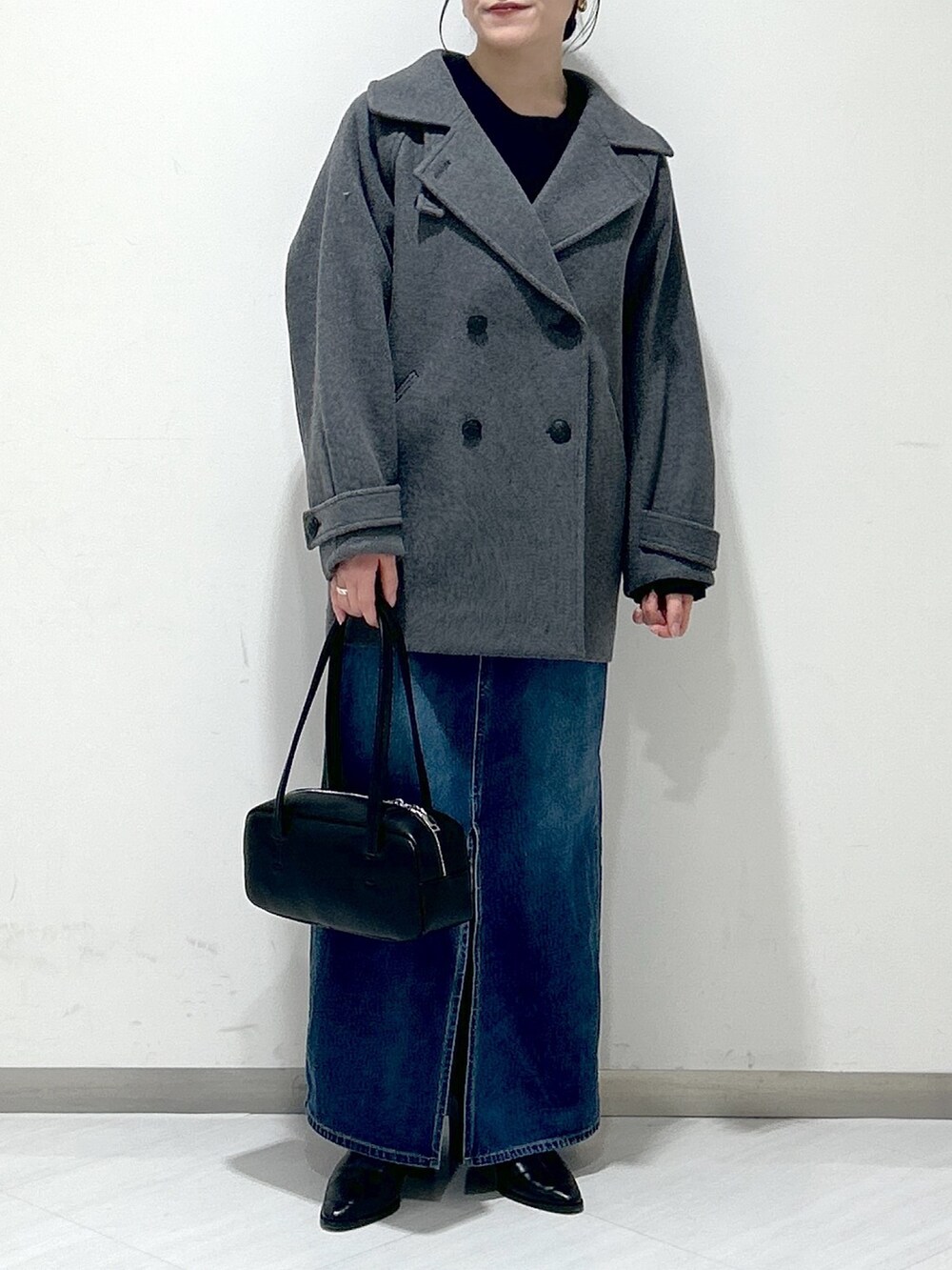 ブルー系のニット/セーター、グレー系のピーコート、ブルー系のデニムスカートを着用したレディースの冬コーディネートの5枚目の写真