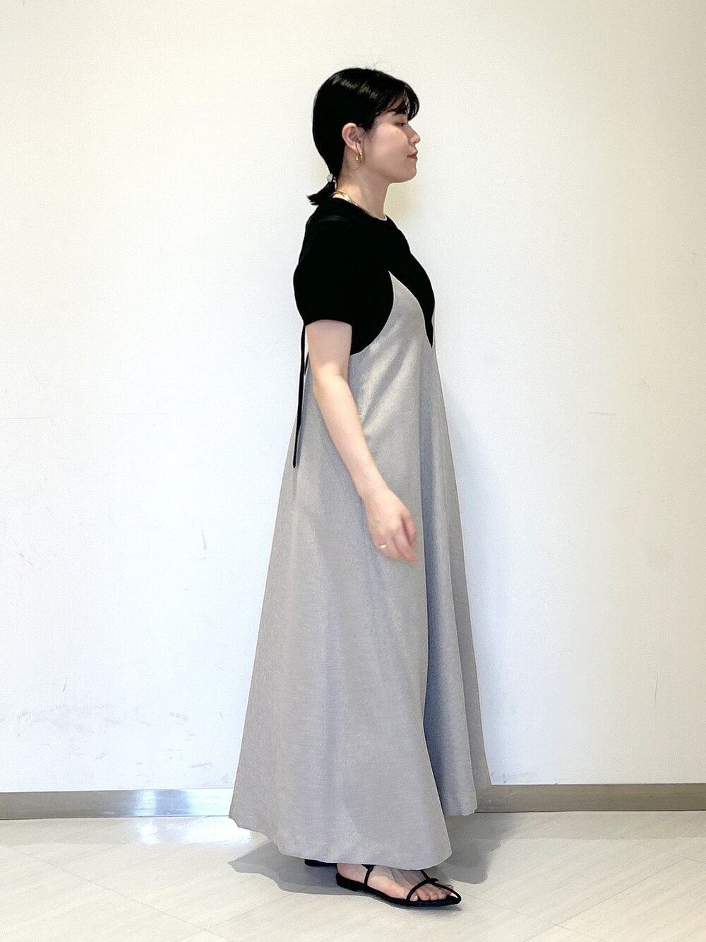 ブラック系のニット/セーター、ブラック系のショルダーバッグ、グレー系のジャンパースカートを着用したレディースの夏コーディネートの5枚目の写真