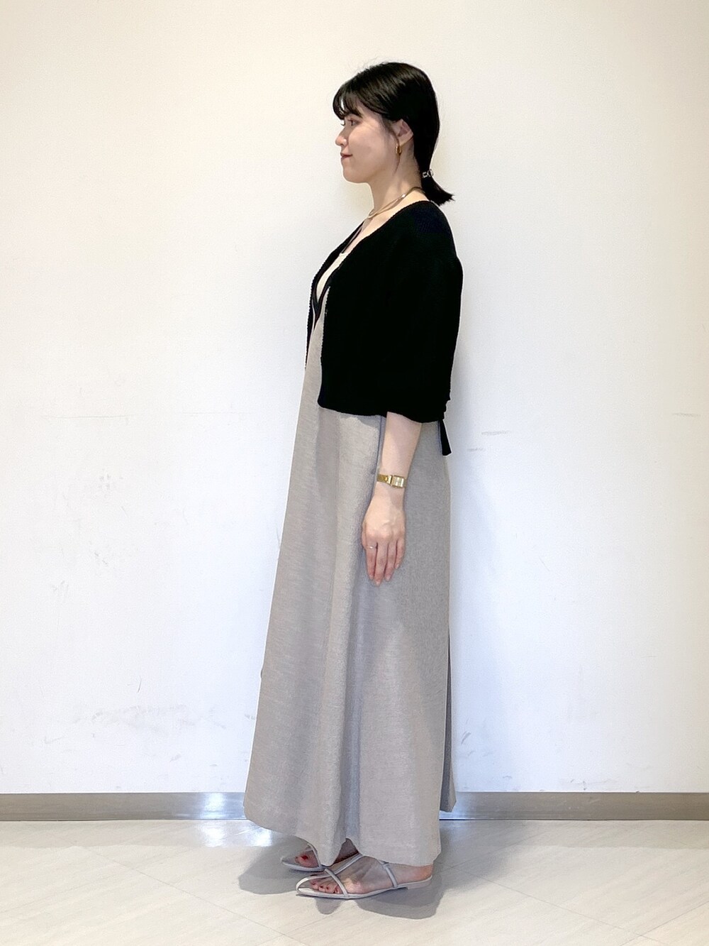 グレー系のジャンパースカート、ブラック系のカーディガン/ボレロ、ベージュ系のタンクトップを着用したレディースの夏コーディネートの3枚目の写真
