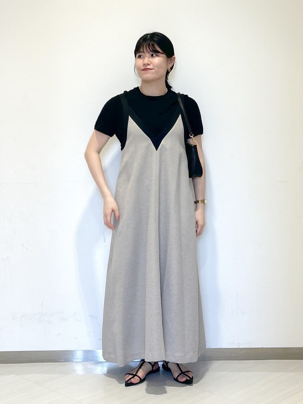 ブラック系のニット/セーター、ブラック系のショルダーバッグ、グレー系のジャンパースカートを着用したレディースの夏コーディネートの6枚目の写真