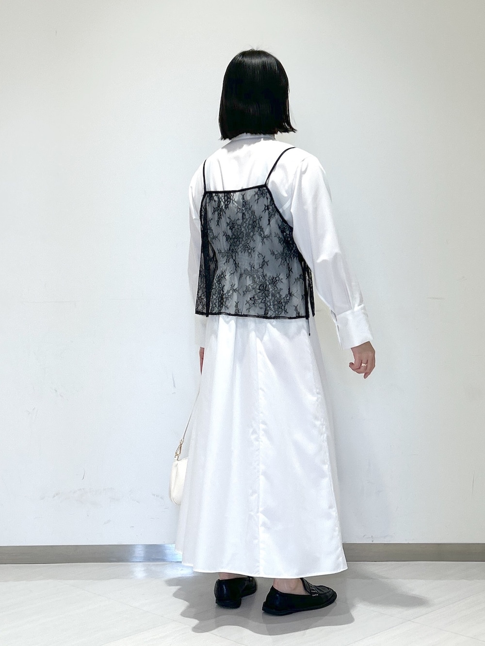 ホワイト系のシャツワンピース、ホワイト系のショルダーバッグ、ブラック系のローファーを着用したレディースの冬コーディネートの3枚目の写真