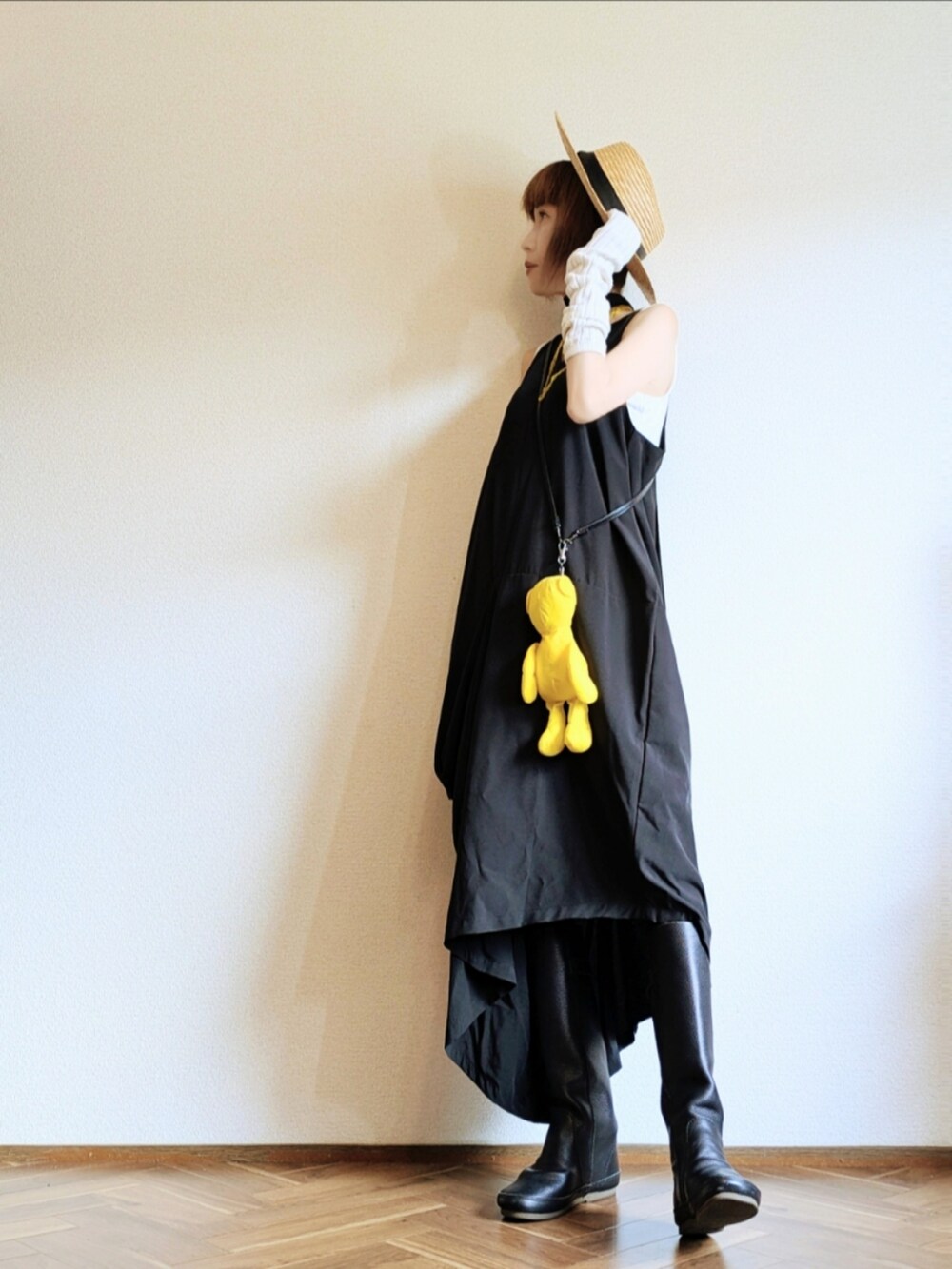 ブラック系のワンピース、イエロー系のエコバッグ/サブバッグ、ブラック系のブーツを着用したレディースの夏コーディネートの3枚目の写真