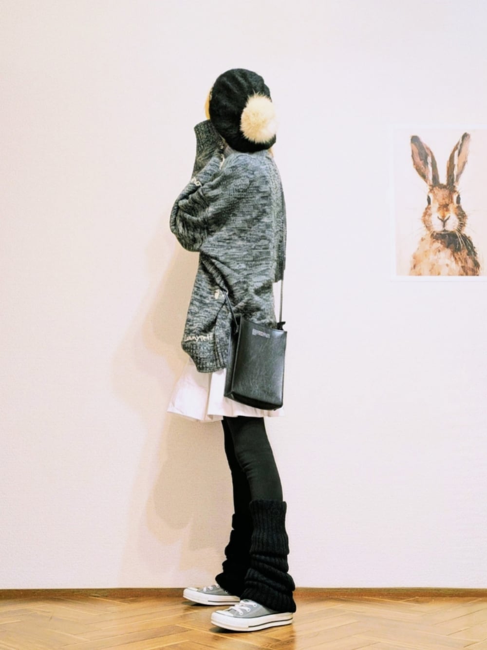 グレー系のニット/セーター、ホワイト系のスカート、グレー系のスニーカーを着用したレディースの冬コーディネートの2枚目の写真