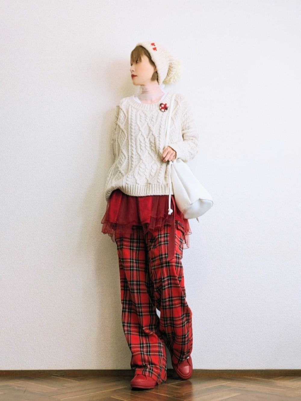 ホワイト系のニット/セーター、レッド系のスカート、レッド系のパンツを着用したレディースの冬コーディネートの2枚目の写真