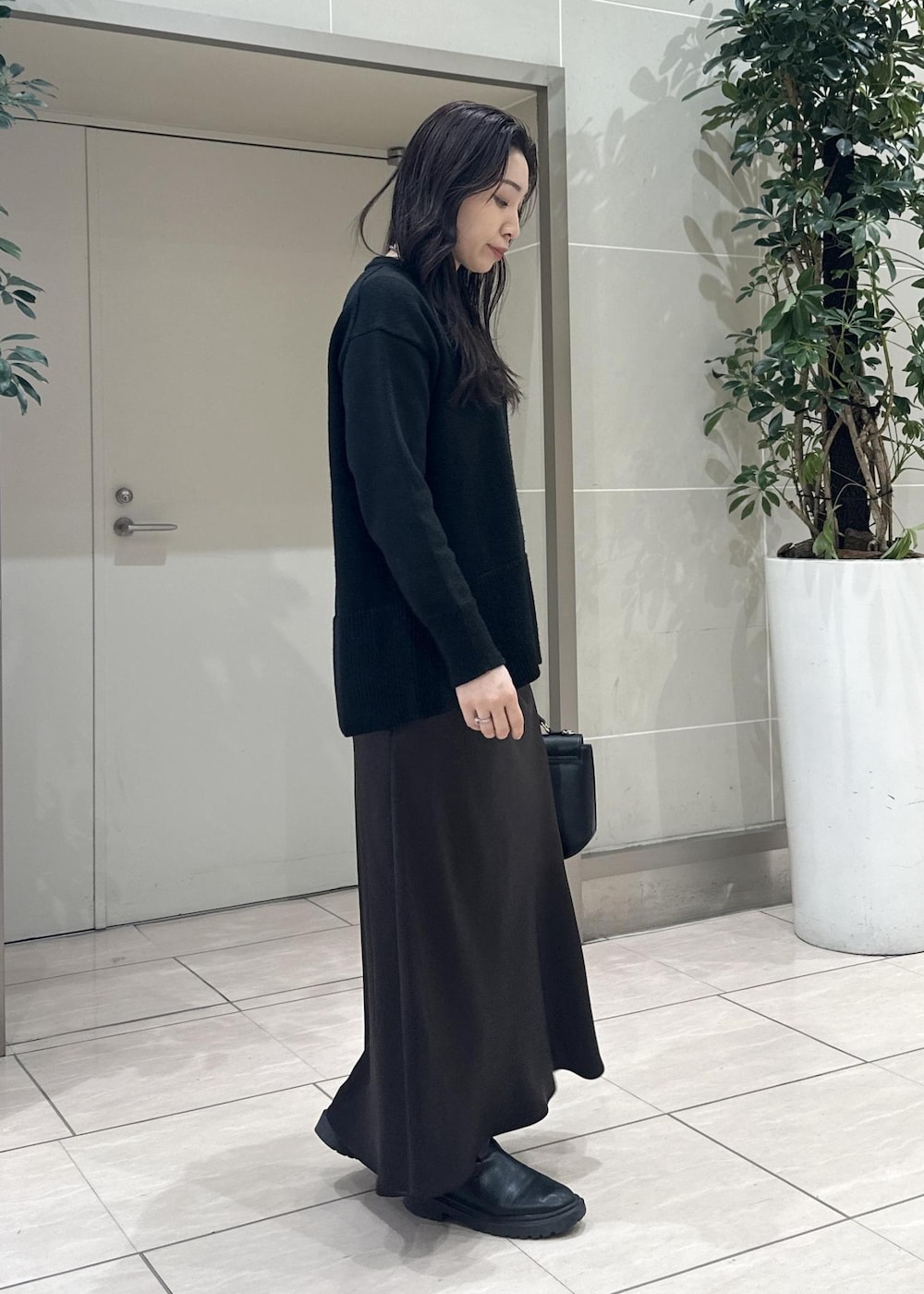 ブラック系のニット/セーター、ブラック系のショルダーバッグ、ブラウン系のスカートを着用したレディースの冬コーディネートの3枚目の写真