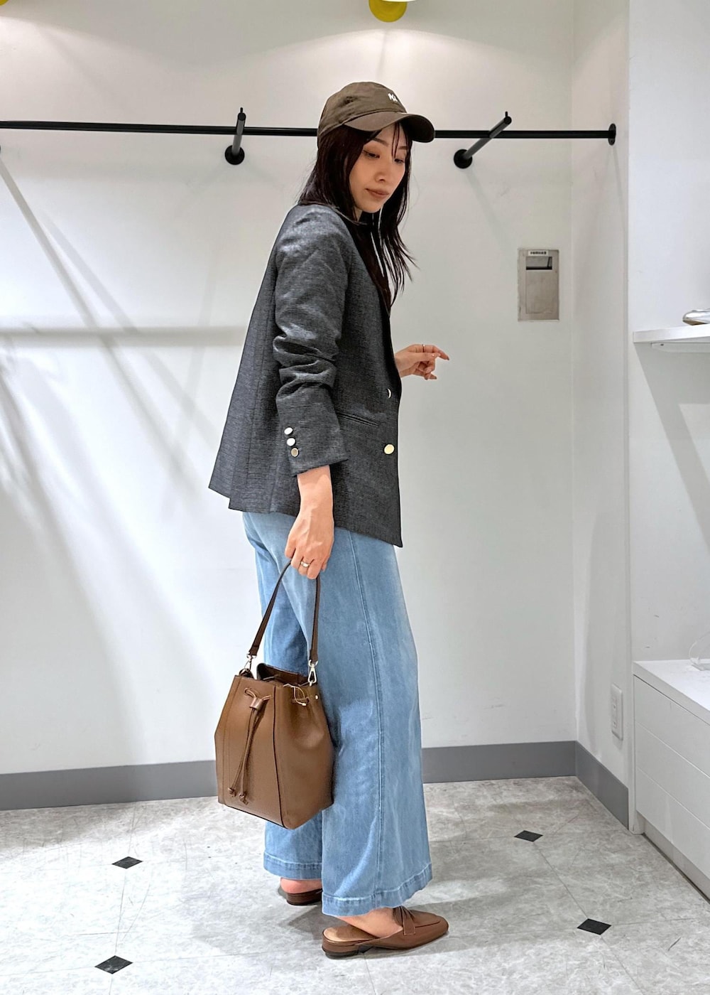 ブルー系のデニムパンツ、イエロー系のローファー、ブラウン系のショルダーバッグを着用したレディースの夏コーディネートの4枚目の写真