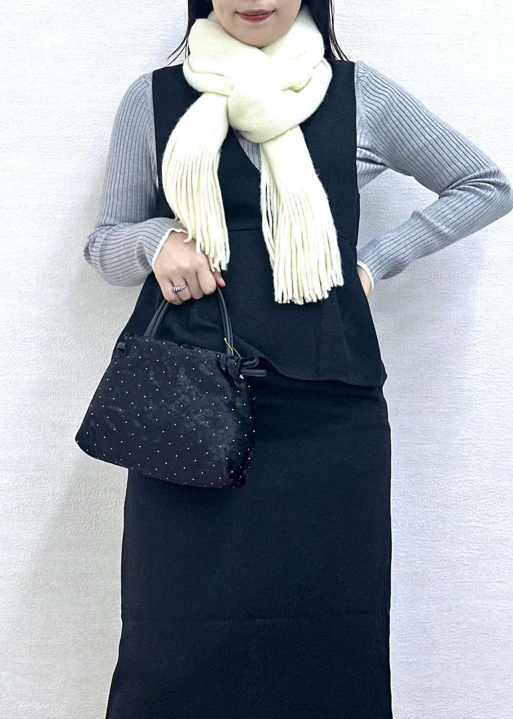 グレー系のニット/セーター、ブラック系のハンドバッグ、ブラック系のジャンパースカートを着用したレディースの冬コーディネートの7枚目の写真