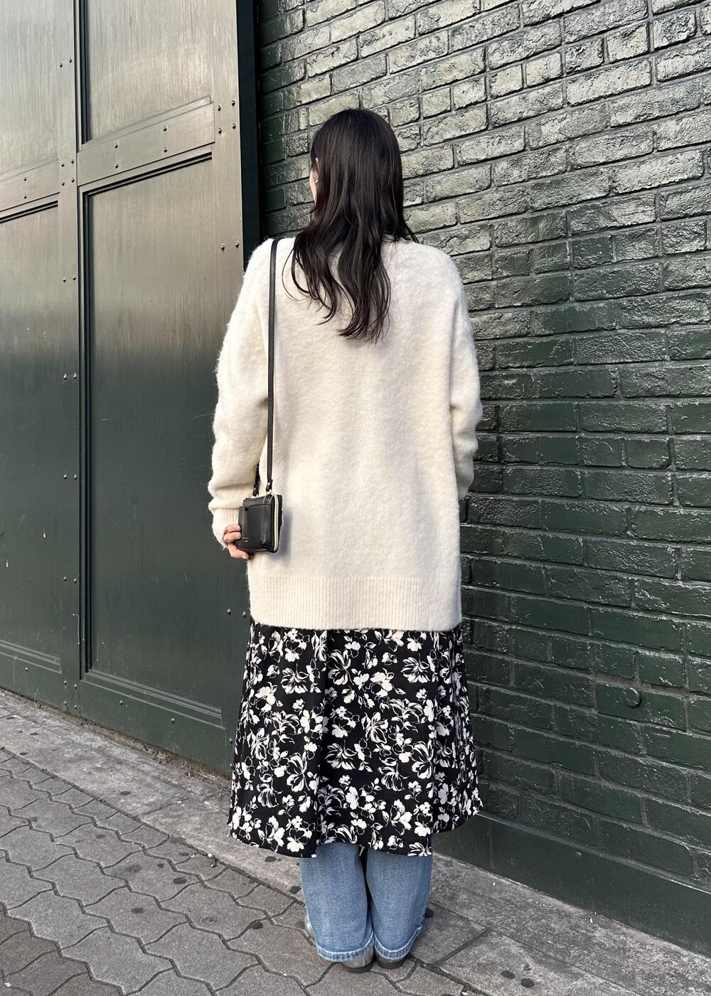 ホワイト系のカーディガン/ボレロ、ブラック系のショルダーバッグ、ブルー系のデニムパンツを着用したレディースの冬コーディネートの3枚目の写真