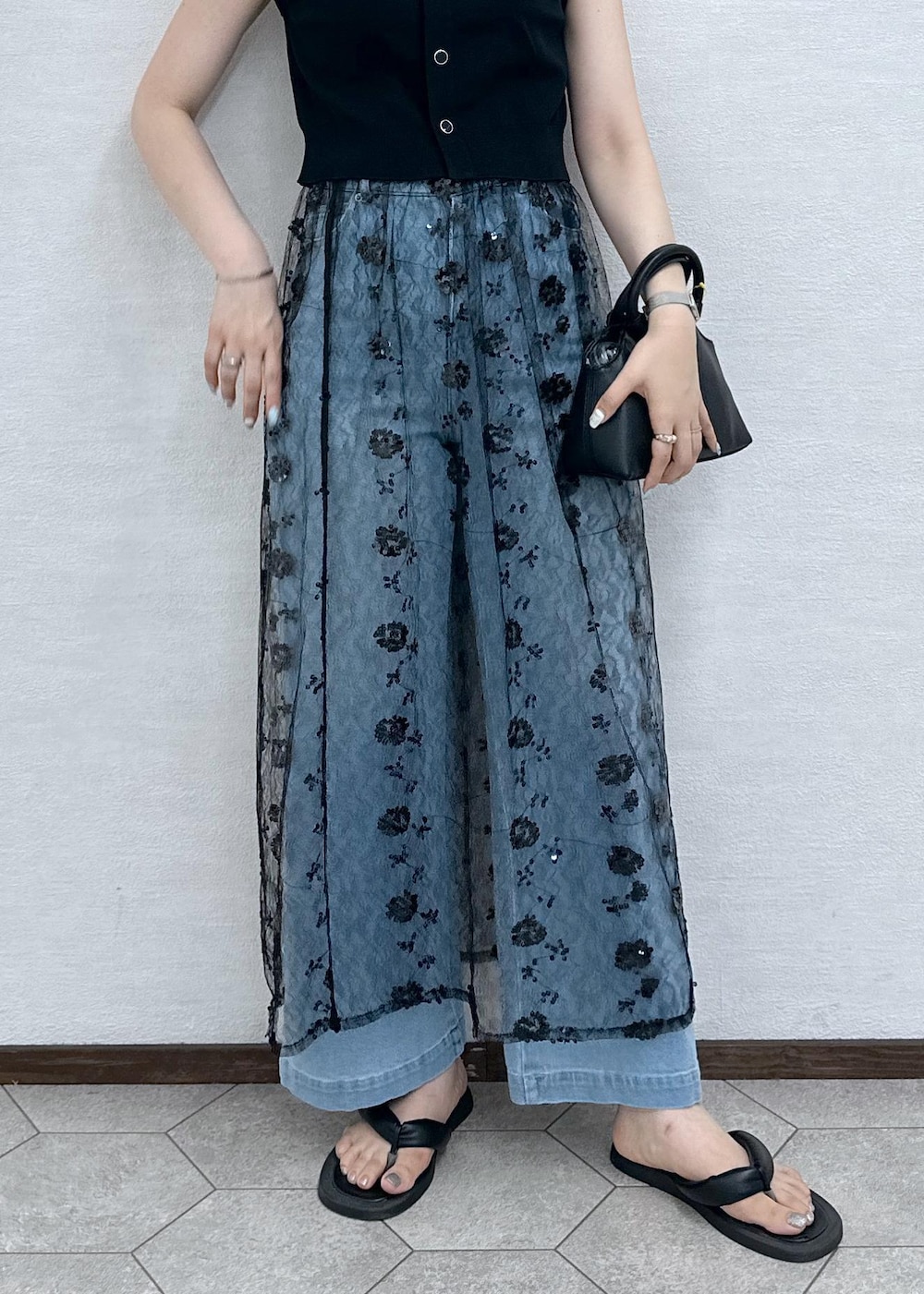 ブルー系のデニムパンツ、ブラック系のベスト、ブラック系のショルダーバッグを着用したレディースの夏コーディネートの9枚目の写真