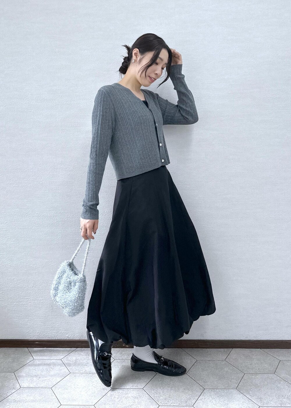 ブラック系のスカート、グレー系のカーディガン/ボレロ、シルバー系のショルダーバッグを着用したレディースの秋コーディネートの3枚目の写真