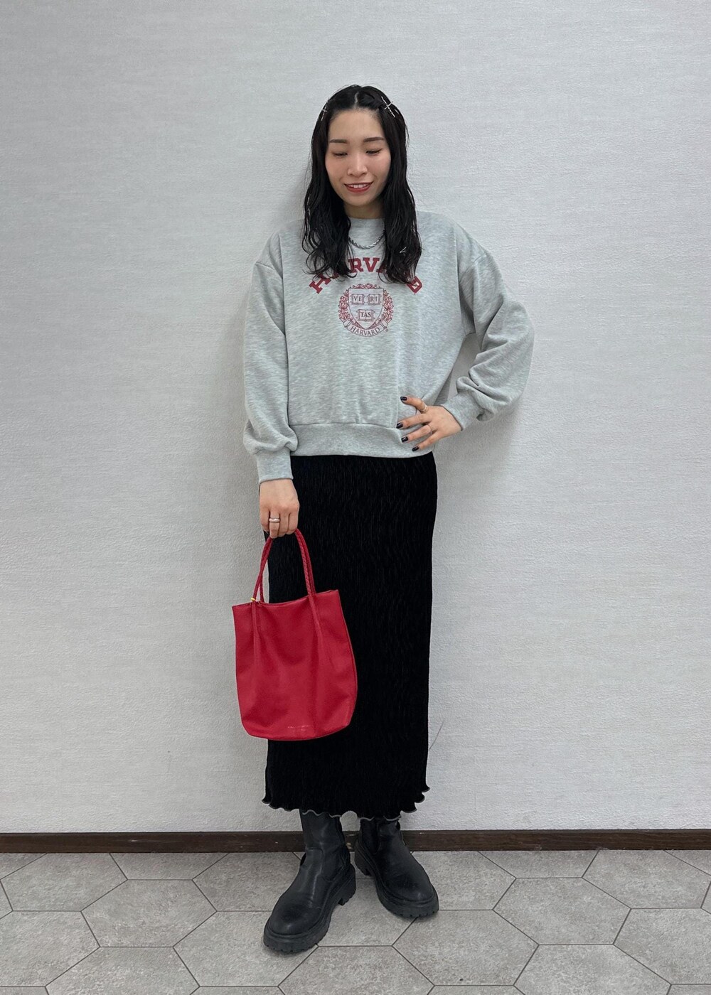 グレー系のスウェット、レッド系のトートバッグ、ブラック系のスカートを着用したレディースの冬コーディネートの2枚目の写真