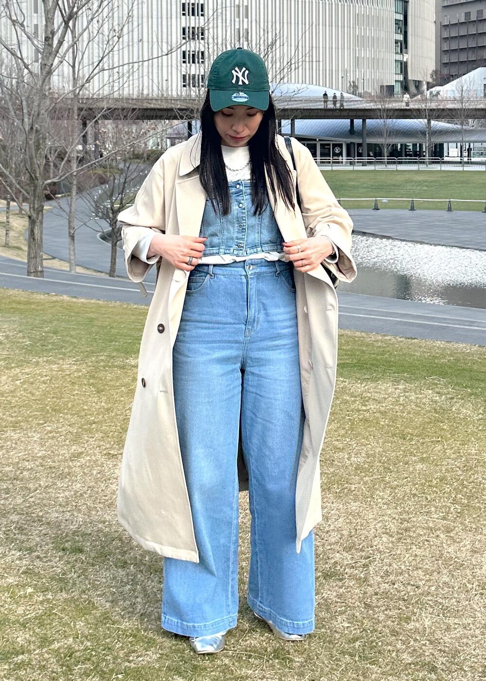 ブラック系のボストンバッグ、ブルー系のベスト、ベージュ系のトレンチコートを着用したレディースの冬コーディネートの2枚目の写真