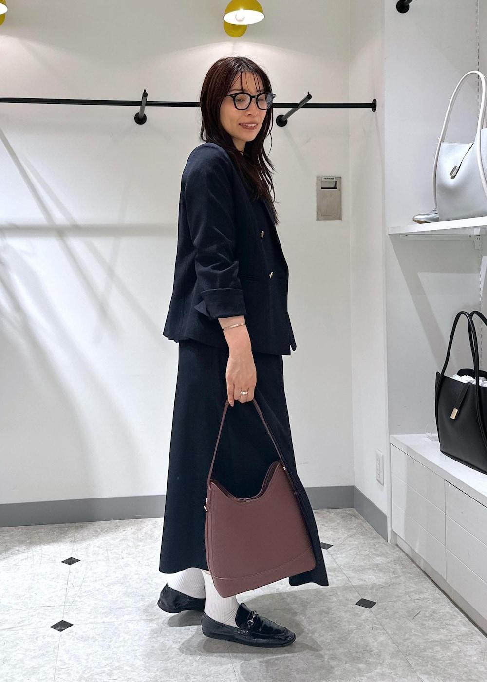 ブルー系のベスト、レッド系のショルダーバッグ、ホワイト系のタンクトップを着用したレディースの夏コーディネートの3枚目の写真