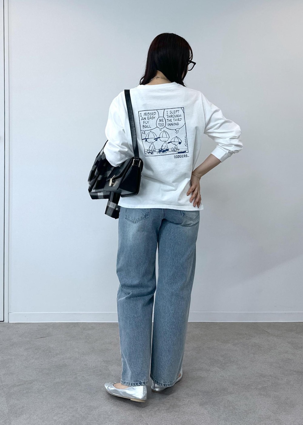 ブルー系のデニムパンツ、シルバー系のバレエシューズ、ブラック系のショルダーバッグを着用したレディースの夏コーディネートの3枚目の写真