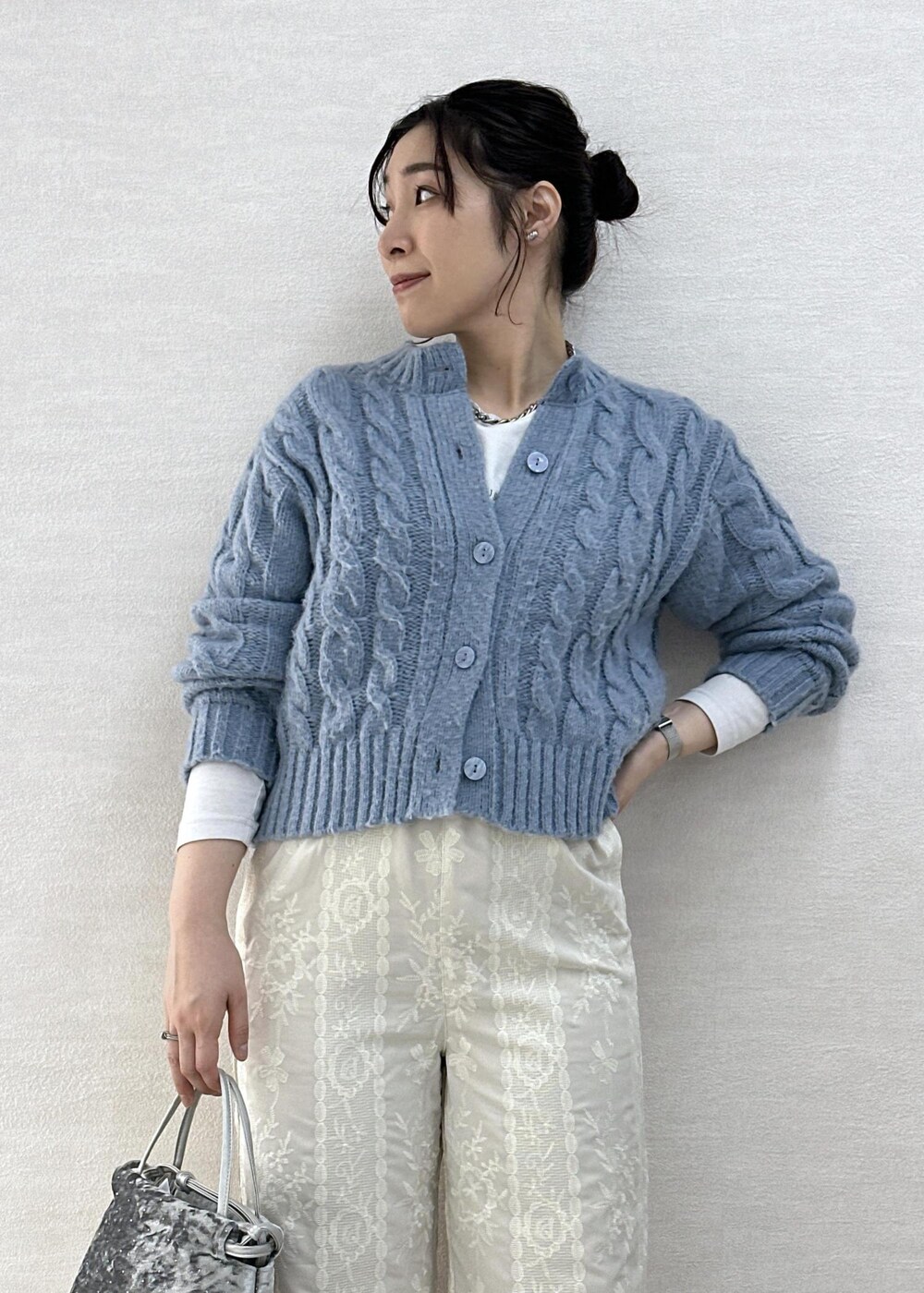 シルバー系のハンドバッグ、ホワイト系のその他パンツ、ブルー系のカーディガン/ボレロを着用したレディースの冬コーディネートの6枚目の写真