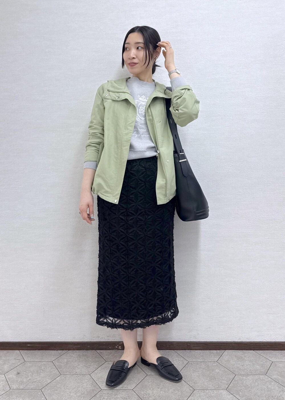 ブラック系のスカート、グレー系のニット/セーター、グリーン系のマウンテンパーカーを着用したレディースの春コーディネートの3枚目の写真