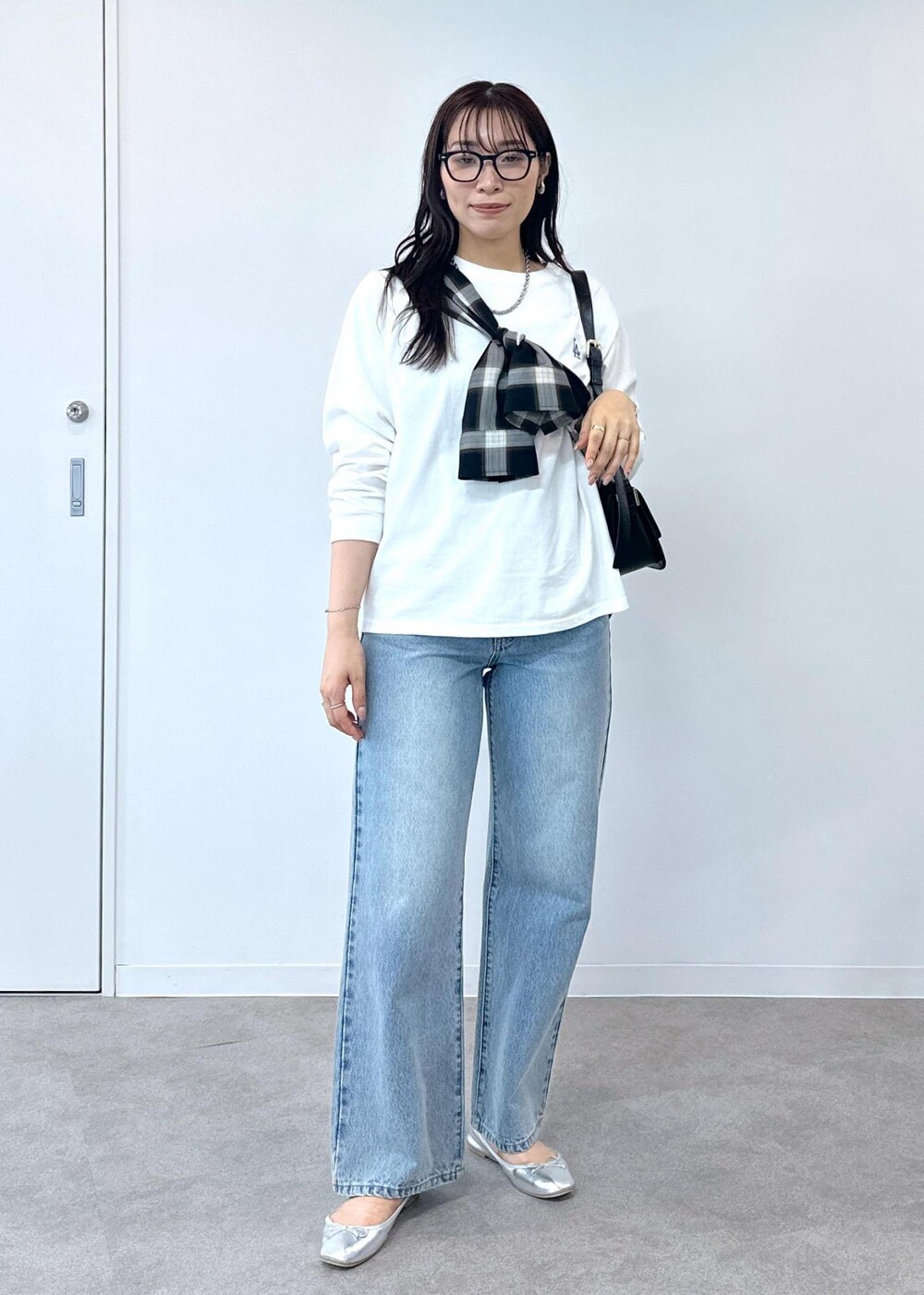 ブルー系のデニムパンツ、シルバー系のバレエシューズ、ブラック系のショルダーバッグを着用したレディースの夏コーディネートの5枚目の写真