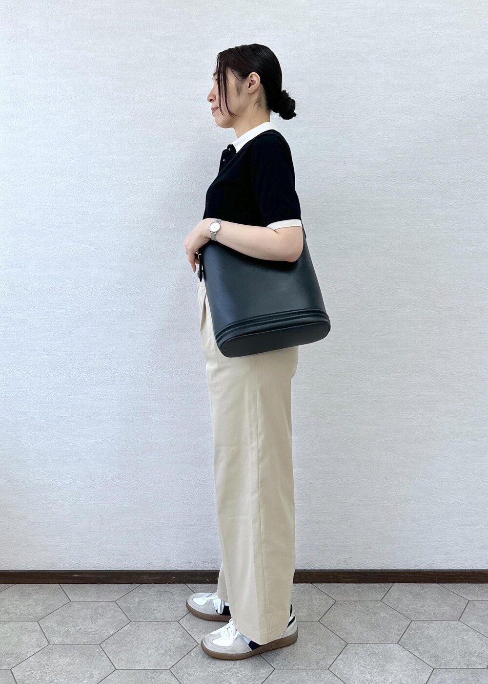 ベージュ系のチノパンツ、ブラック系のトートバッグ、ブラック系のポロシャツを着用したレディースの春コーディネートの4枚目の写真
