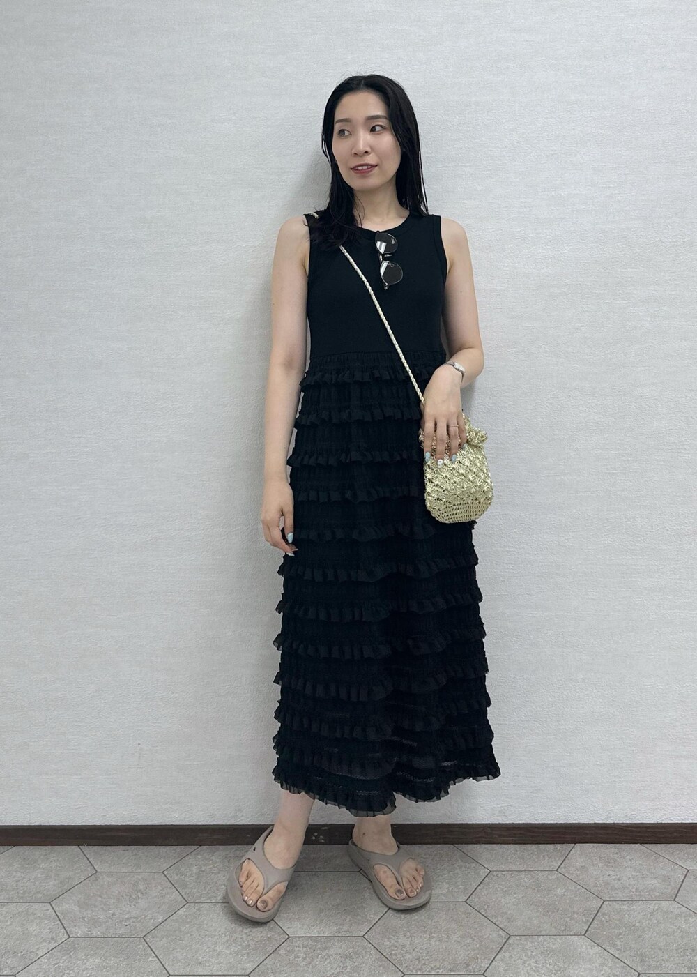 ゴールド系のショルダーバッグ、ブラック系のワンピース、ブラウン系のサングラスを着用したレディースの夏コーディネートの2枚目の写真