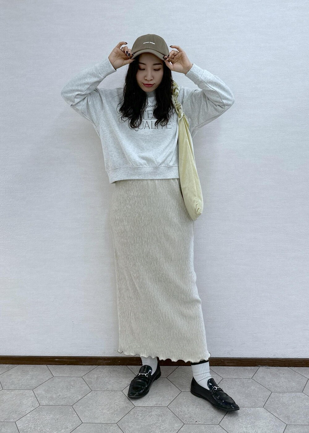 イエロー系のショルダーバッグ、グレー系のスウェット、ホワイト系のスカートを着用したレディースの冬コーディネートの3枚目の写真