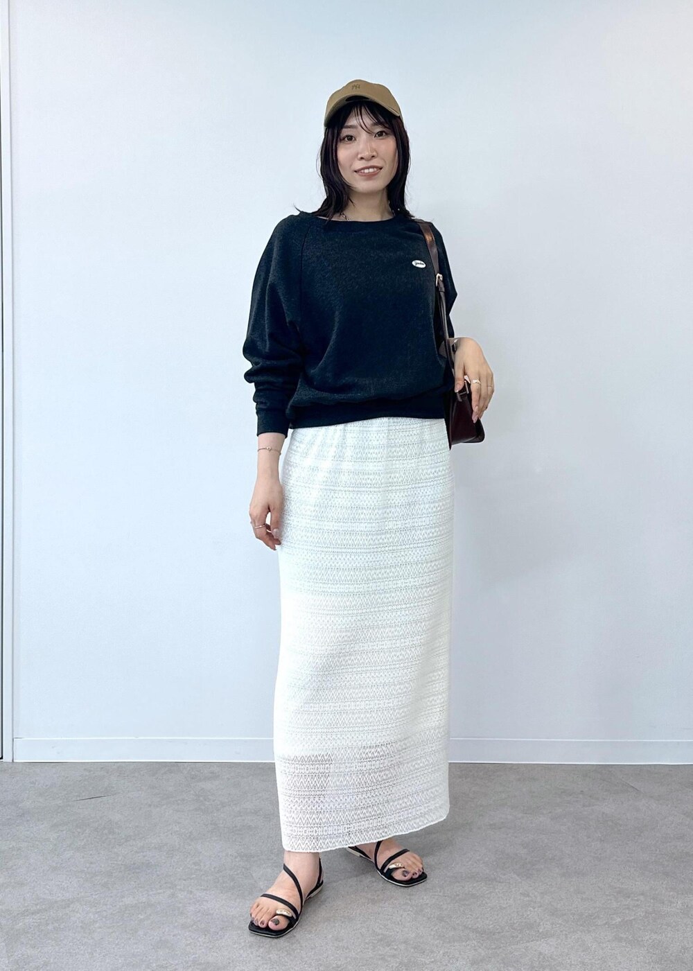 ブラック系のサンダル、ホワイト系のスカート、レッド系のショルダーバッグを着用したレディースの夏コーディネートの2枚目の写真