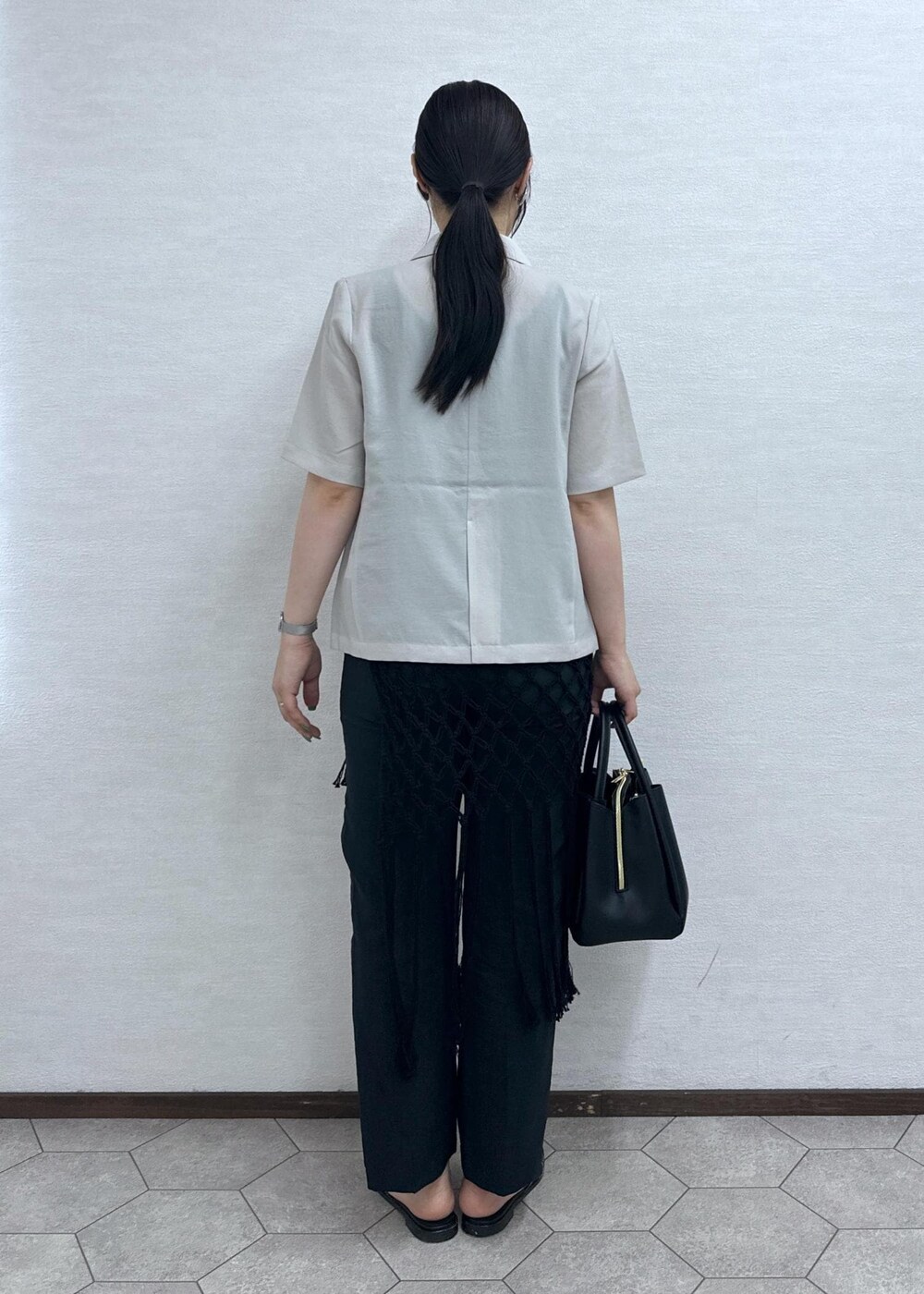 ブラック系のショルダーバッグ、ベージュ系のテーラードジャケット、グレー系のその他パンツを着用したレディースの夏コーディネートの5枚目の写真