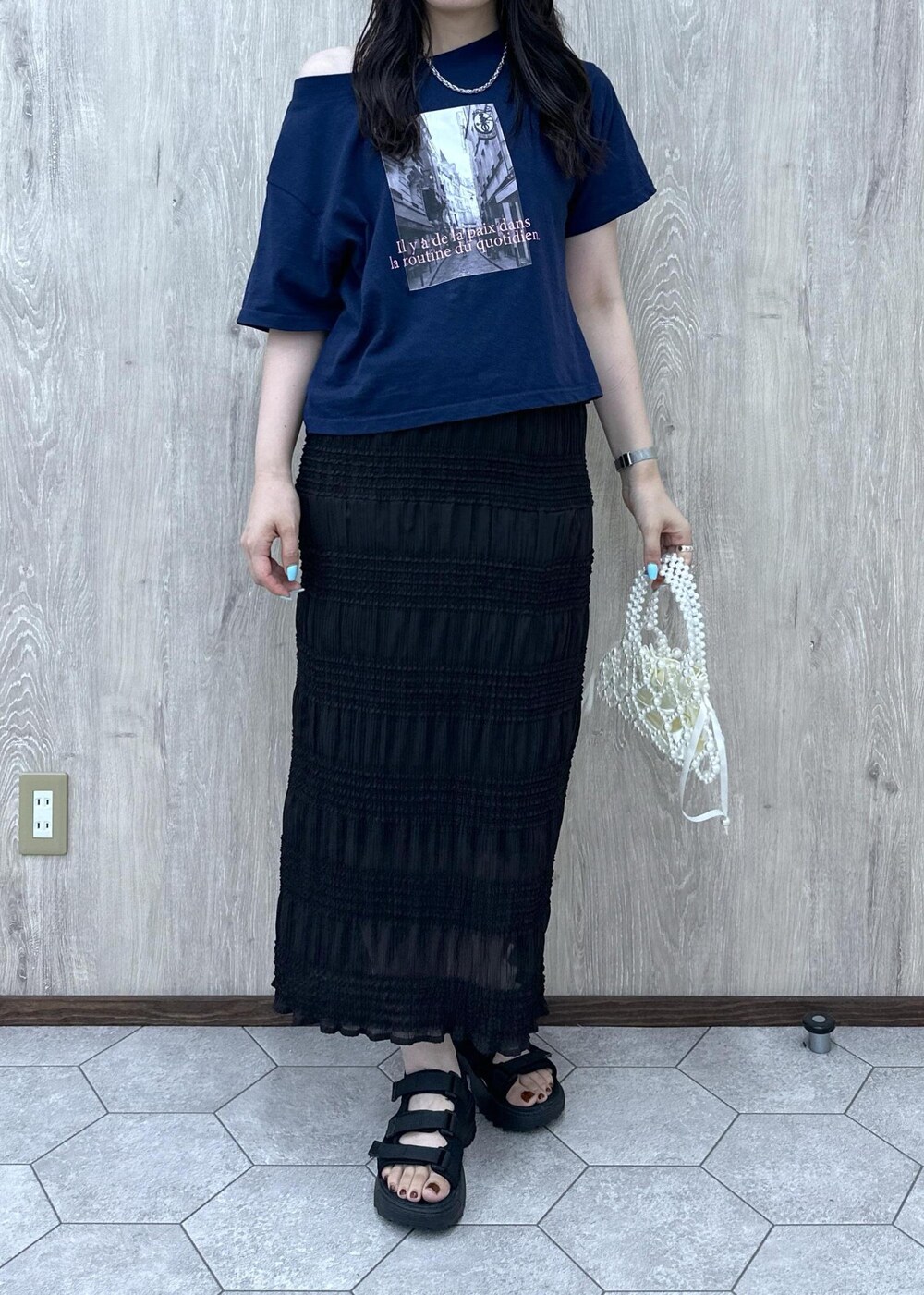 ホワイト系のハンドバッグ、グレー系のスカート、ブラック系のサンダルを着用したレディースの夏コーディネートの6枚目の写真
