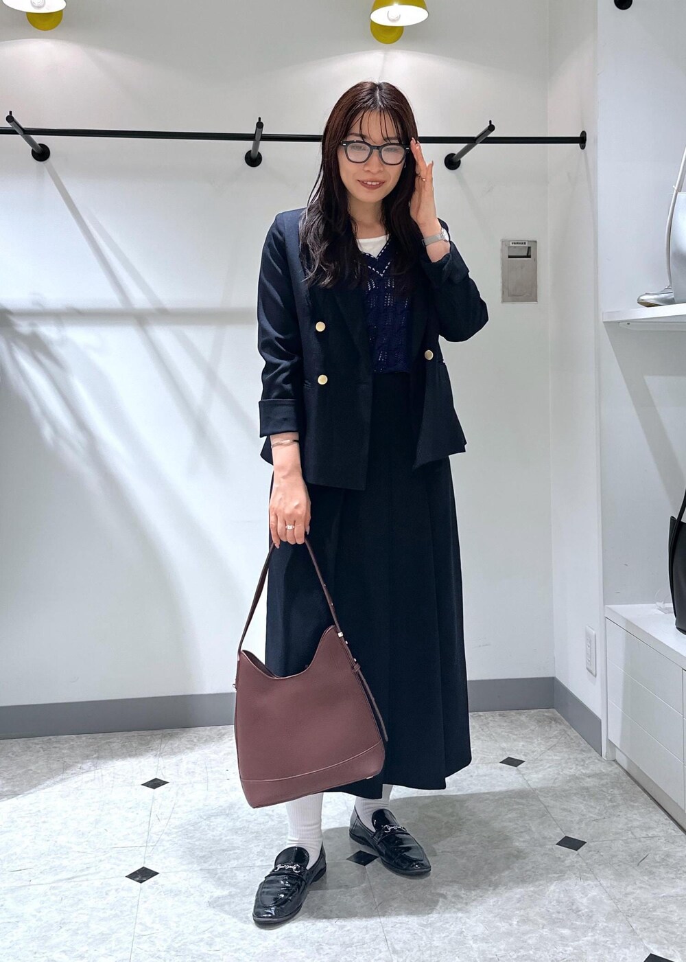 ブルー系のベスト、レッド系のショルダーバッグ、ホワイト系のタンクトップを着用したレディースの夏コーディネートの4枚目の写真