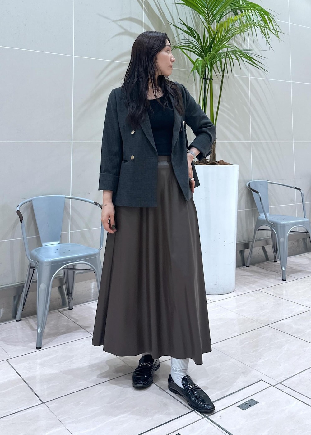 ブラック系のショルダーバッグ、ブラック系のテーラードジャケット、ブラウン系のスカートを着用したレディースの秋コーディネートの4枚目の写真