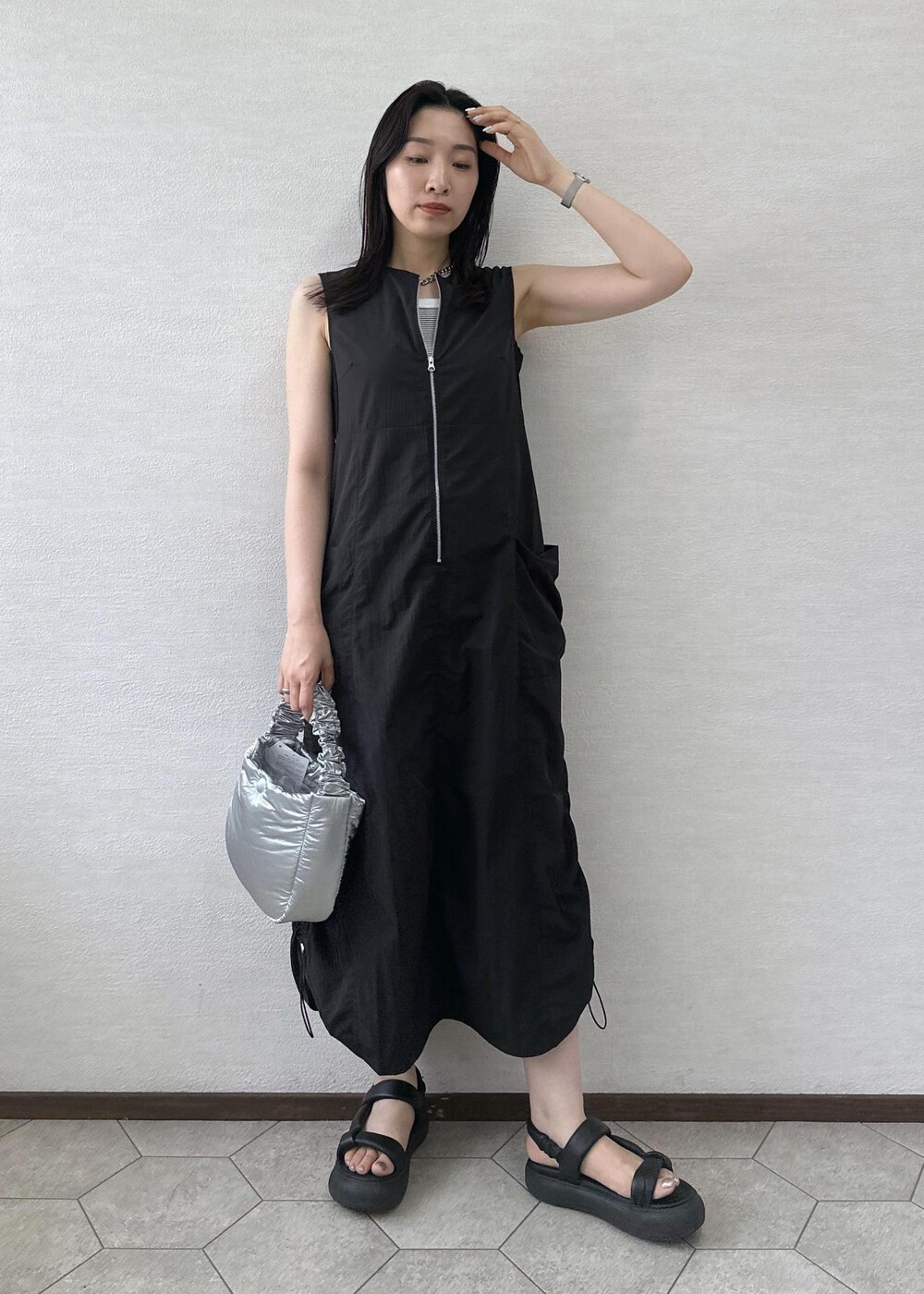 ブラック系のワンピース、シルバー系のショルダーバッグを着用したレディースの夏コーディネートの2枚目の写真