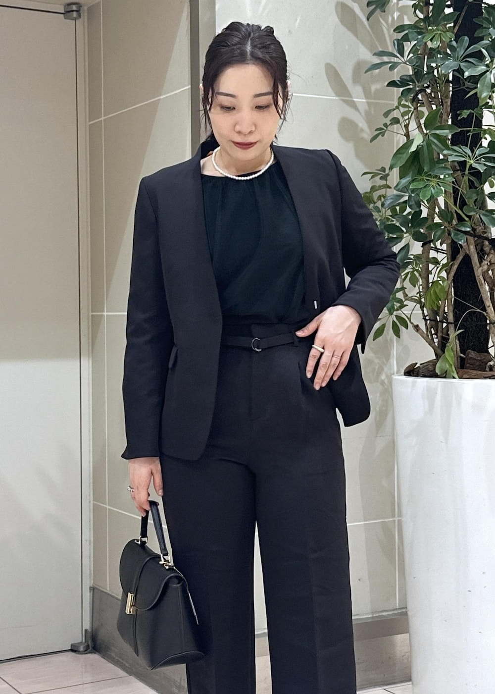 ブラック系のニット/セーター、ブラック系のローファー、ブラック系のノーカラージャケットを着用したレディースの冬コーディネートの10枚目の写真