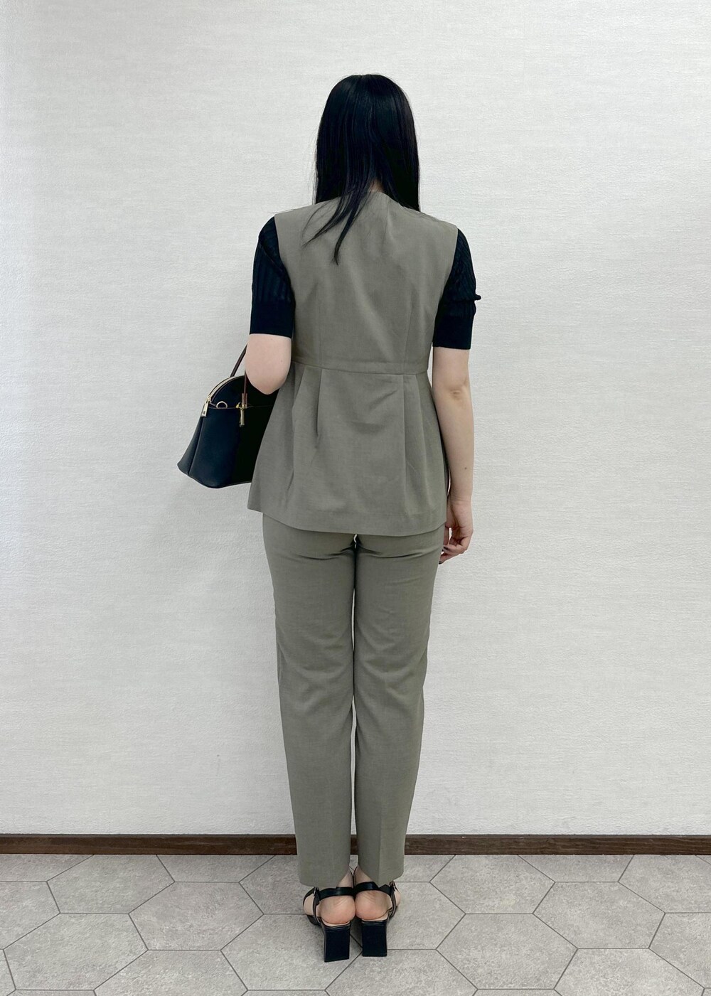 ブラック系のショルダーバッグ、ブラック系のニット/セーター、ブラウン系のその他パンツを着用したレディースの春コーディネートの3枚目の写真