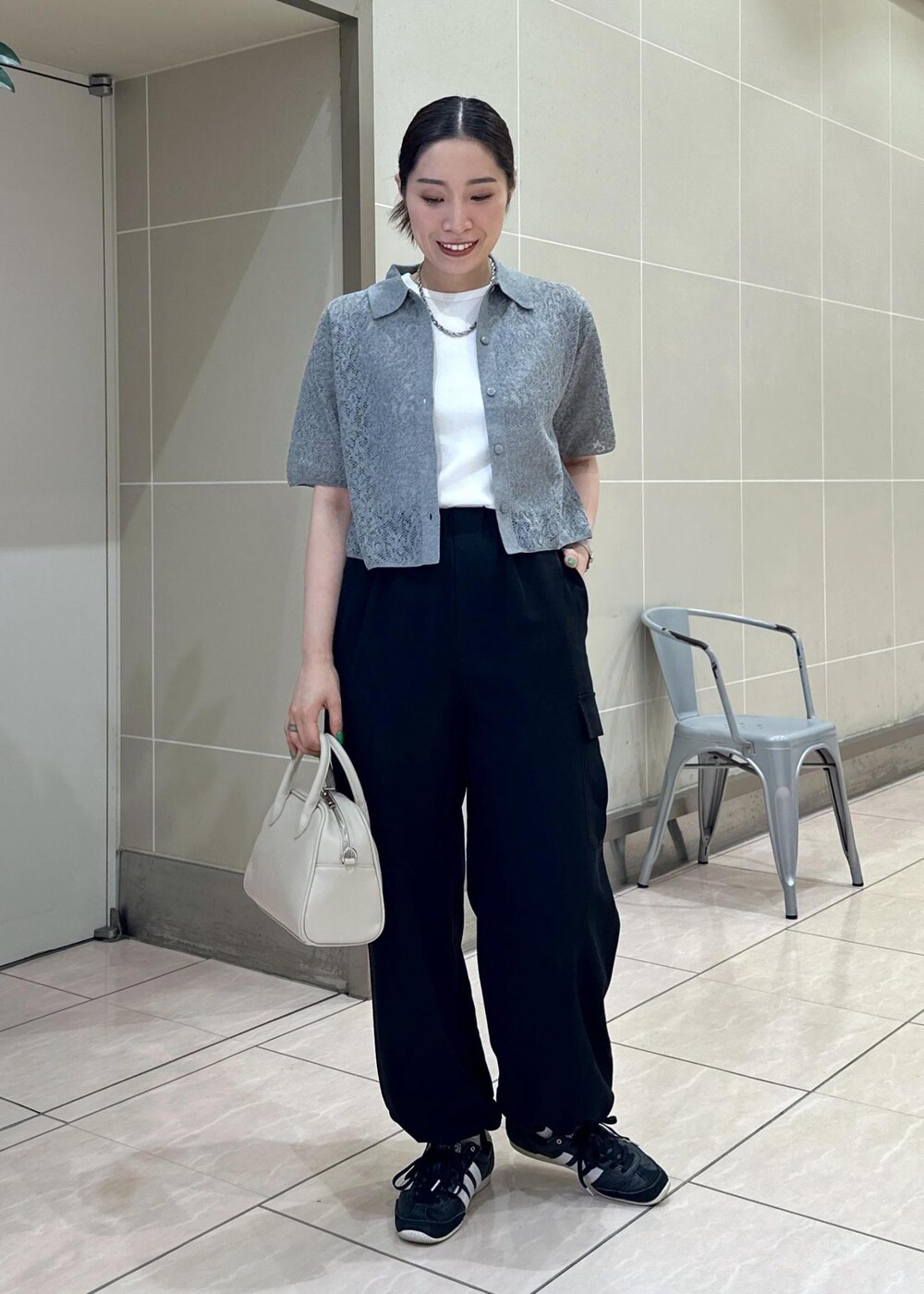 ベージュ系のボストンバッグ、ブラック系のカーゴパンツ、ホワイト系のタンクトップを着用したレディースの夏コーディネートの2枚目の写真