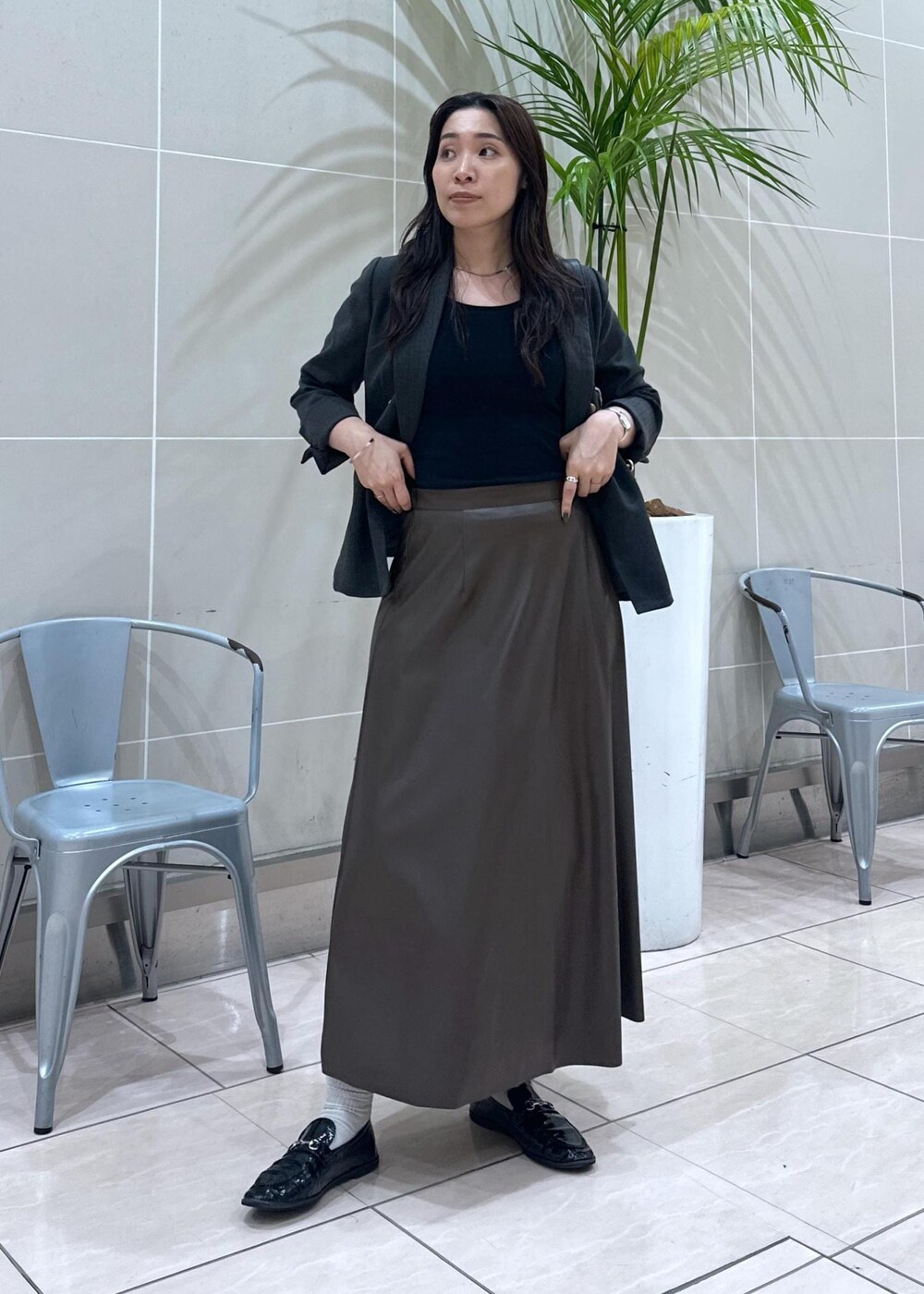 ブラック系のショルダーバッグ、ブラック系のテーラードジャケット、ブラウン系のスカートを着用したレディースの秋コーディネートの3枚目の写真