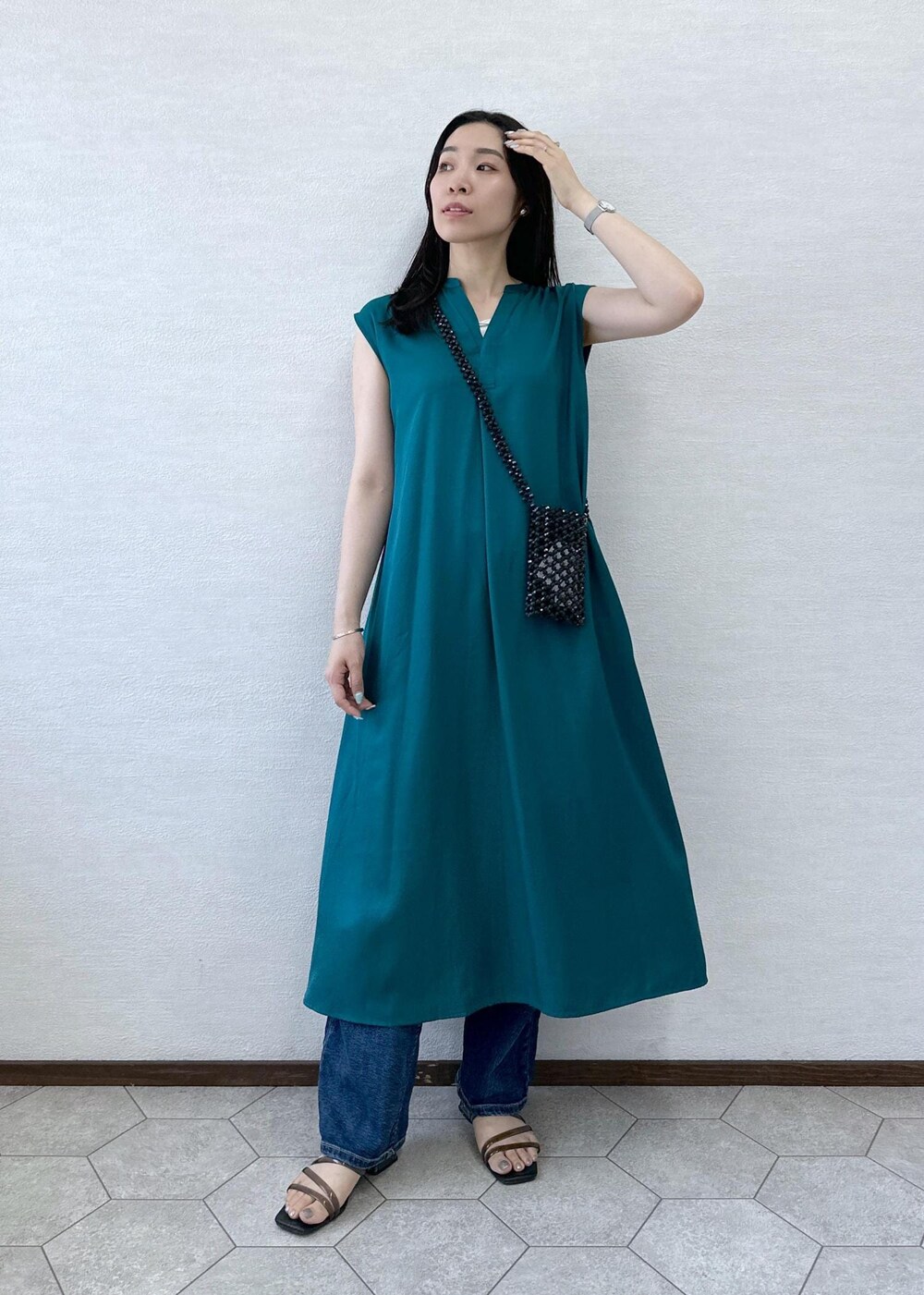 ブラック系のショルダーバッグ、ブルー系のデニムパンツ、グリーン系のワンピースを着用したレディースの夏コーディネートの3枚目の写真