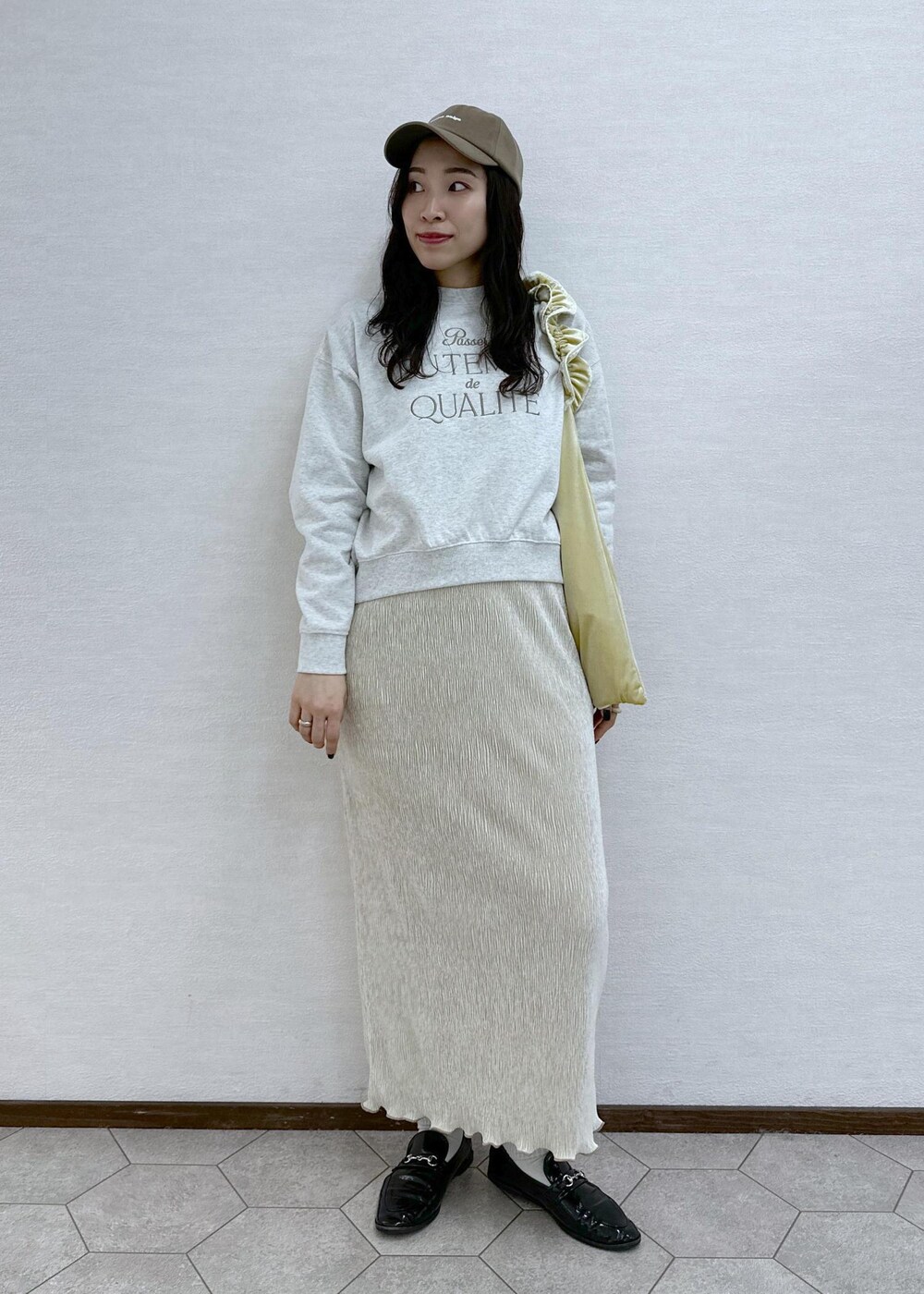 イエロー系のショルダーバッグ、グレー系のスウェット、ホワイト系のスカートを着用したレディースの冬コーディネートの2枚目の写真